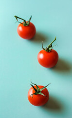 Three red tomatoes on a green background, vertical format