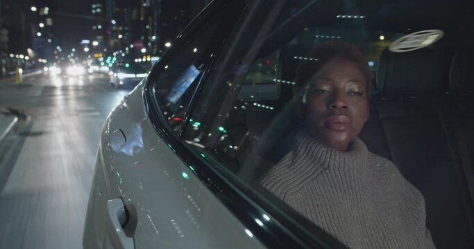 Young Black Woman Passenger Talking To The Driver As They Travel Through The City Center In The Night