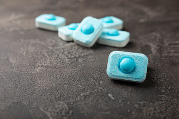 Water softener tablets on black texture background. Capsules for washing machines and dishwashers,...