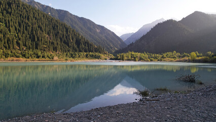 View of the mountain lake Issyk from a height. Turquoise-emerald water from the glacier. Reflection...