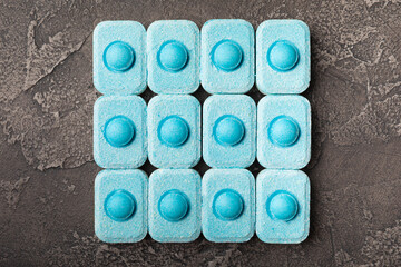 Water softener tablets on black texture background. Capsules for washing machines and dishwashers,...