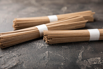 Buckwheat paste on a black cement background. Raw noodles. Ingredients for a gluten-free dish. Dried buckwheat soba noodles. Traditional Japanese food. Healthy food. Place to copy.