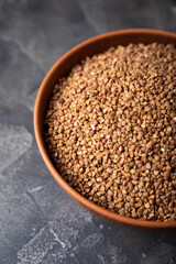 Buckwheat in a bowl on a black textured marble background. Raw buckwheat. Ingredients for gluten free cereal. Healthy food. Place to copy.