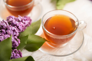 A cup of green tea against the background of a spring bouquet of lilacs . Romantic composition with books and candles. spring tea drink. Place to copy. Romantic concept.