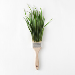 Creative composition with green grass and paint brush on white background. Minimal nature concept, flat lay