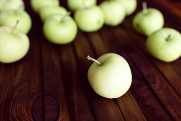 Lots of ripe green apples on a wooden background.	