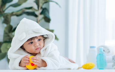 Adorable caucasian little baby daughter girl, wearing cute white bathrobe, taking bath in morning, crawling on floor with copy space, smiling with happiness at home or house. Kid Development Concept.