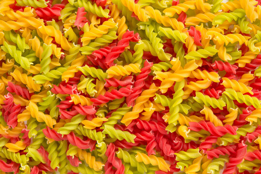 Close-up background of Fusille and Rotini in a glass bowl on white. pasta colorata	