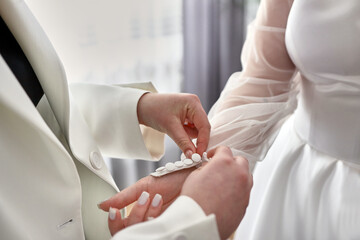 Fototapeta premium A friend helps the bride to fasten buttons on the wrist of a wedding dress.