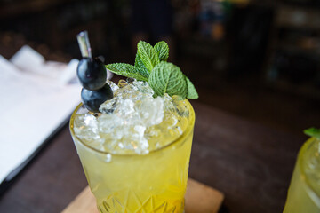 Glass of cocktail with ice. Mojito with ice on a wooden tabletop on a dark background.