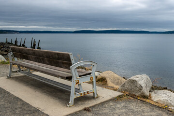 Angled view behind a wooden park bench with the Tacoma city skyline off in the horizon