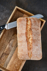 ItaliItalian ciabatta bread in a wooden box with a knife. Freshly baked traditional bread. Shallow depth of field