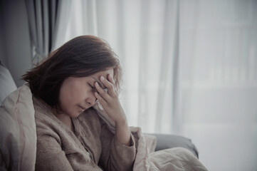 Asian sick woman sit on the sofa stay at home,The woman felt bad, wanted to lie down and rest,high fever