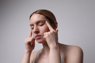 Headshot of young woman touches her face and deep thinking. Mindset concept.
