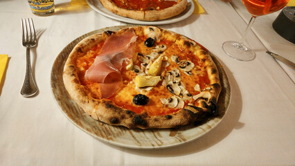 pizza capricciosa with prosciutto ham, black olives, artichoke, cheese and tomato sauce