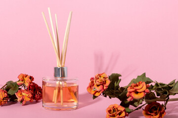 Obraz na płótnie Canvas reed diffuser with flowers. Incense sticks for the home with a floral scent with hard shadows. The concept of eco-friendly fragrance for the home