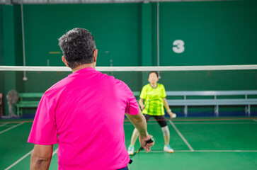 the elderly playing badminton in the badminton court The portraits are shifted and the focus is soft.
