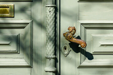 Ancient wooden double front door with cast iron door handle in the shape of a lions head