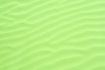 Green tinted sand ripples created by the wind in the fine beach sand by the sea