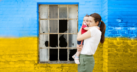 Worried Ukrainian mother holding her child in front of a destroyed window