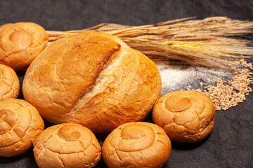 Culinary background with bread,sweet bun,wheat ears,grains on a black background, top view
