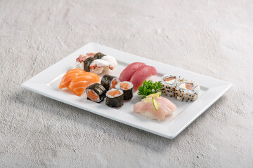 Sushi mix on white plate. Studio shoot isolated on slate background. Salmon, tuna, octopus and white fish different kinds of sushi. Oriental food on Brazilian way!