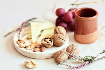 Walnuts, red grapes, cheese and a jar of honey are on a light background. Appetizer with wine.