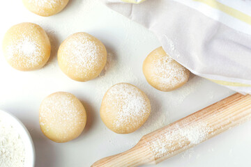Balls of mz dough, rolling pin and flour are on the kitchen table. View from the top point.