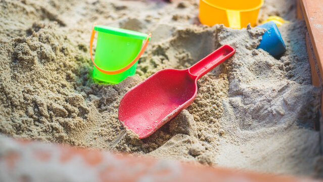 Children plastic toys in the sand box. Shovel, selective focus.
