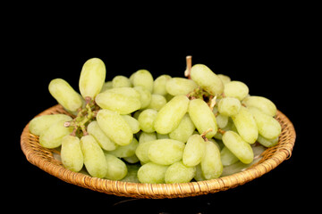 One bunch of white seedless grapes on a ceramic dish, close-up, isolated on a black background.