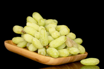 One bunch of white seedless grapes on a bamboo tray, close-up, isolated on a black background.