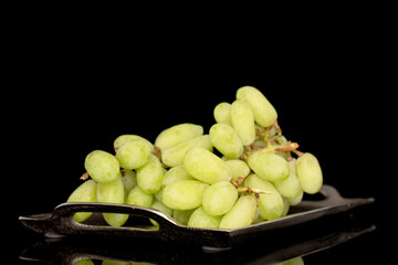 One bunch of white seedless grapes on a metal tray, close-up, isolated on a black background.