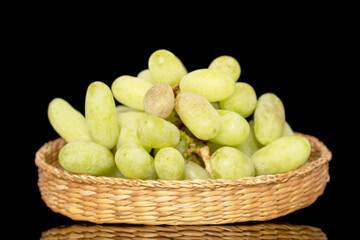 One bunch of white seedless grapes in a straw bowl, close-up, isolated on a black background.