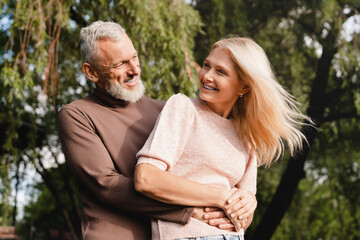 Heterosexual couple. Caucasian mature spouses hugging embracing together in city park on romantic date. Love and relationship concept.