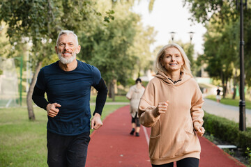 Active seniors. Caucasian mature couple running jogging together, doing slimming exercises in...
