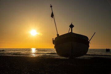 Kuter Rybacki na tle zachodzącego słońca nad polskim morzem w Rewalu