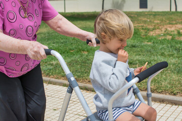 Obraz premium Grandmother with walker playing with her great grandson. Old lady with walker walking in the park.