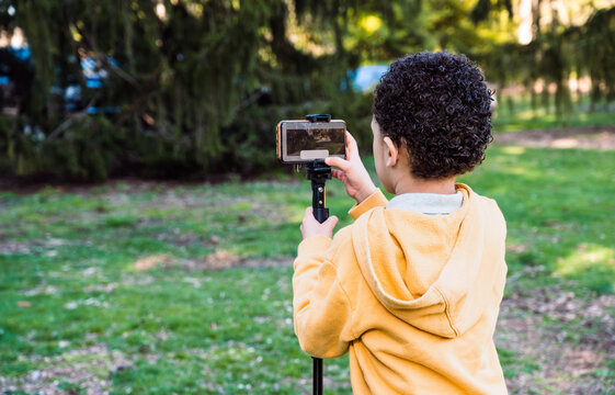 Young boy photographer taking photos with cellphone  outdoors in the nature copy space.