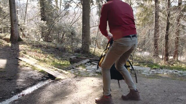 The guy ties the laces on brown boots standing on one knee on the ground.