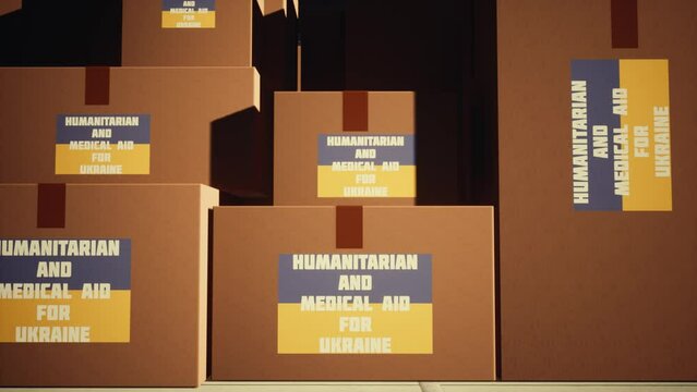 Large cardboard boxes with the inscription humanitarian and medical assistance for Ukraine. In the background is an airplane and workers.