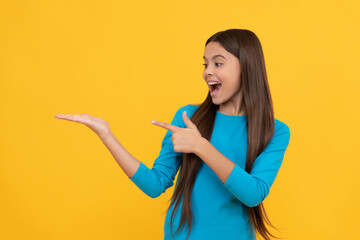 amazed kid presenting product and point finger on copy space. beauty and fashion.