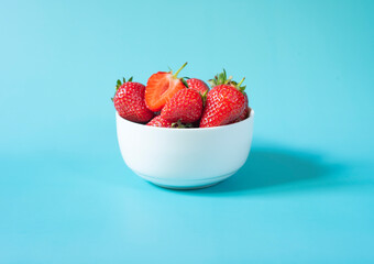 Fresh organic strawberries in pot on light blue background