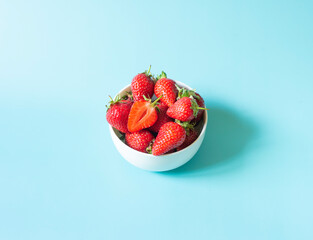 Fresh organic strawberries in pot on light blue background