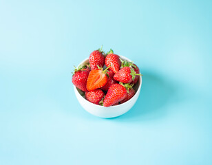 Fresh organic strawberries in pot on light blue background