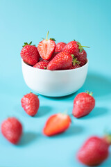 Fresh organic strawberries in pot on light blue background