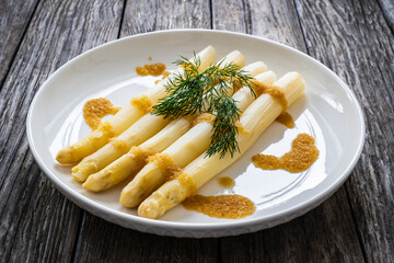 White boiled asparagus in breadcrumbs with butter served on wooden table