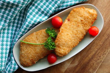 Crumbed hake fillets with salad tomatoes and parsley 