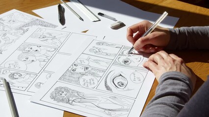 The artist draws sketches of comic book characters on paper. The illustrator creates a storyboard.