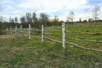 Fototapeta na wymiar Fence made of birch poles and wooden poles.
