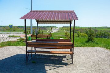 Comfortable resting place near the highway. Wooden table and bench under the roof.
